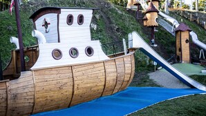 A wooden ship-shaped play structure with slides and climbing areas.