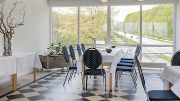 A dining area with a checkered floor, white tablecloths, and blue chairs.