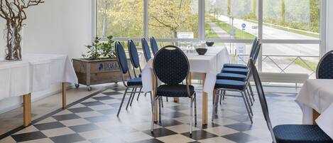 A dining area with a checkered floor, white tablecloths, and blue chairs.