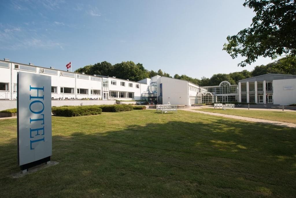 A hotel with a prominent 'HOTEL' sign, a modern building with a flat roof, and a well-maintained lawn.