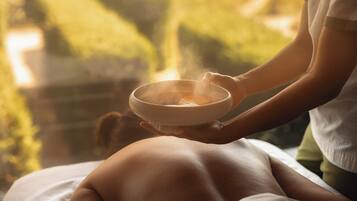 A person receiving a hot stone massage with a bowl of hot stones.