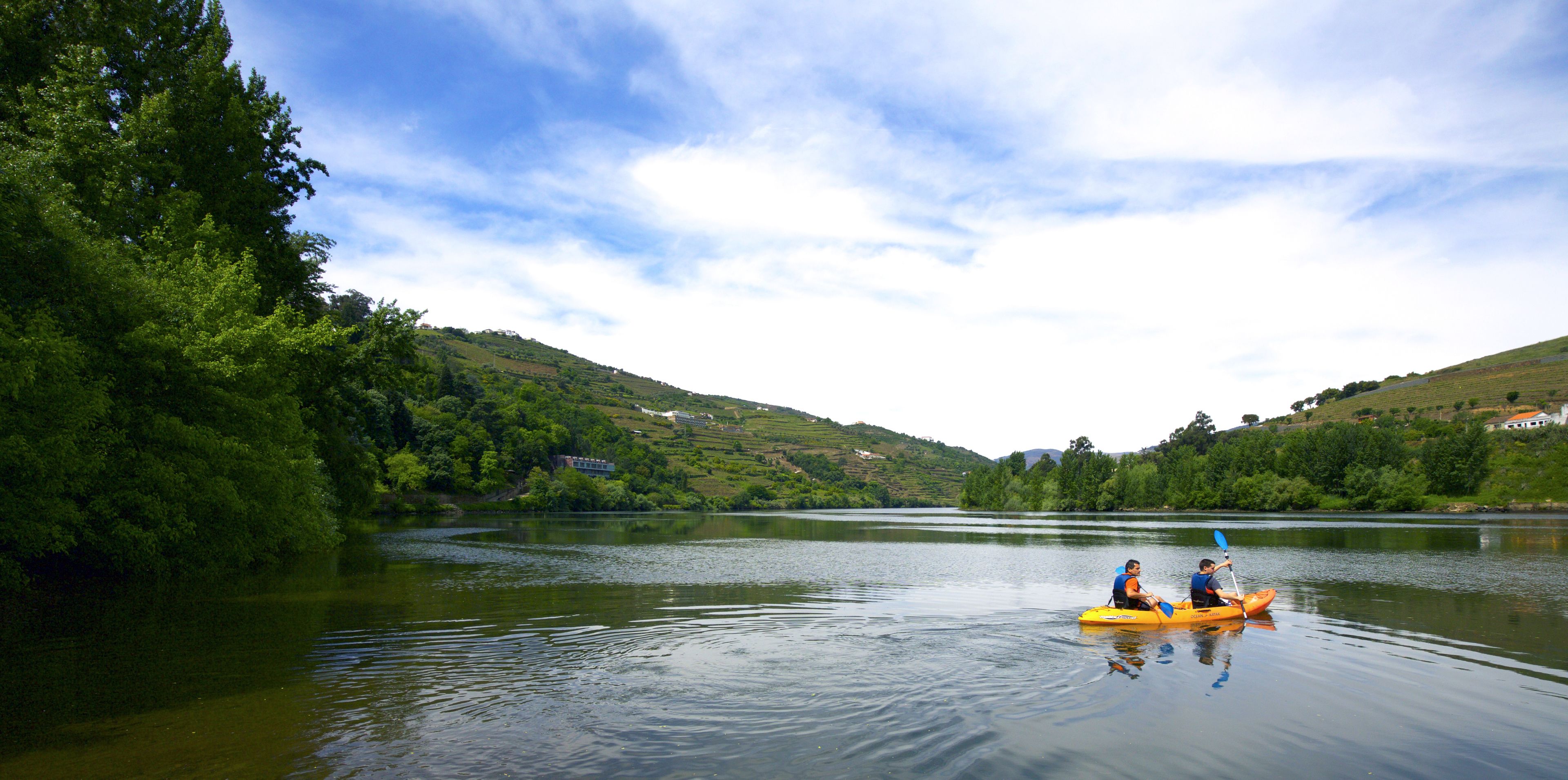 A calm river with a kayak and two people paddling.