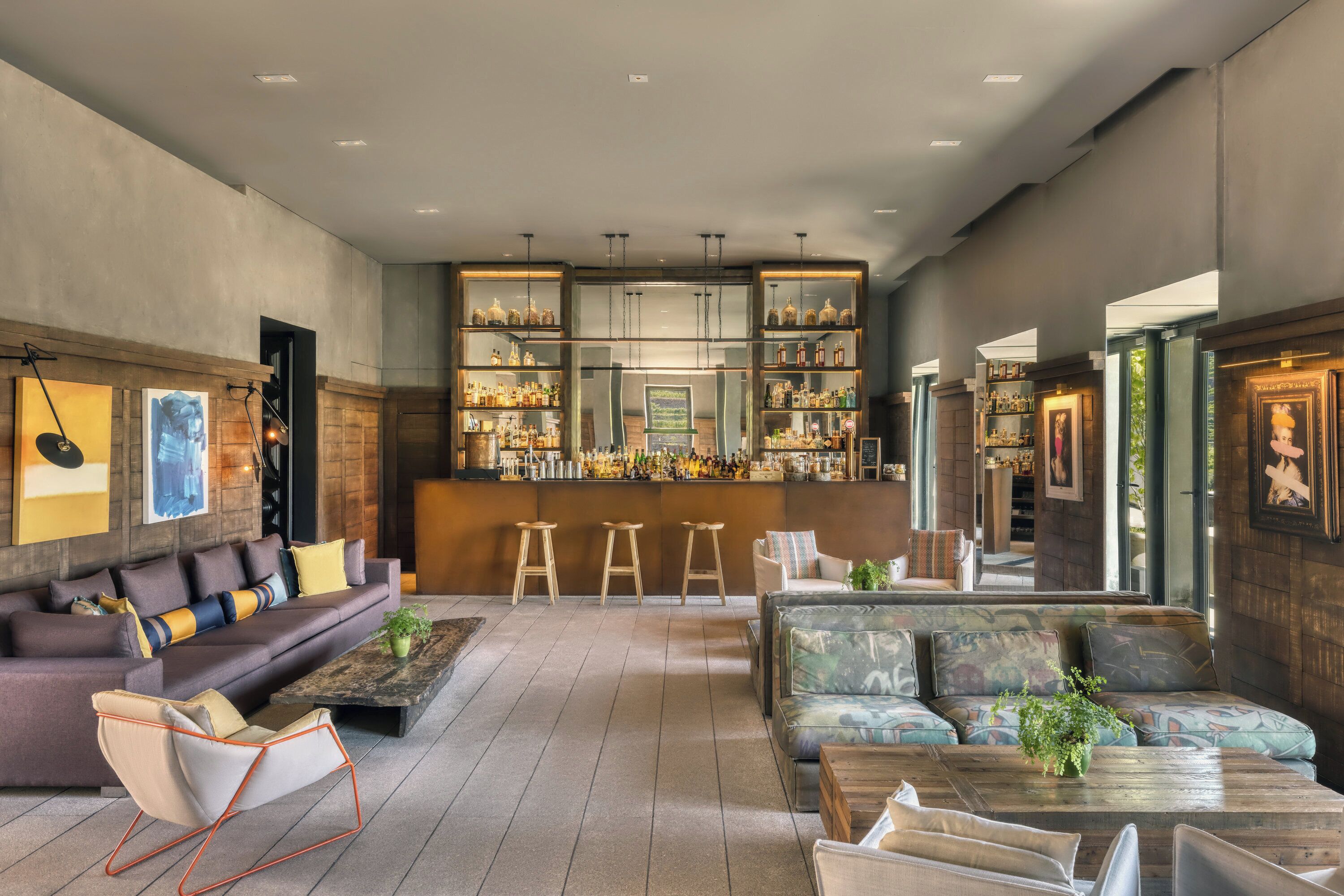 A modern bar area with a bar counter, shelves of bottles, and stools.