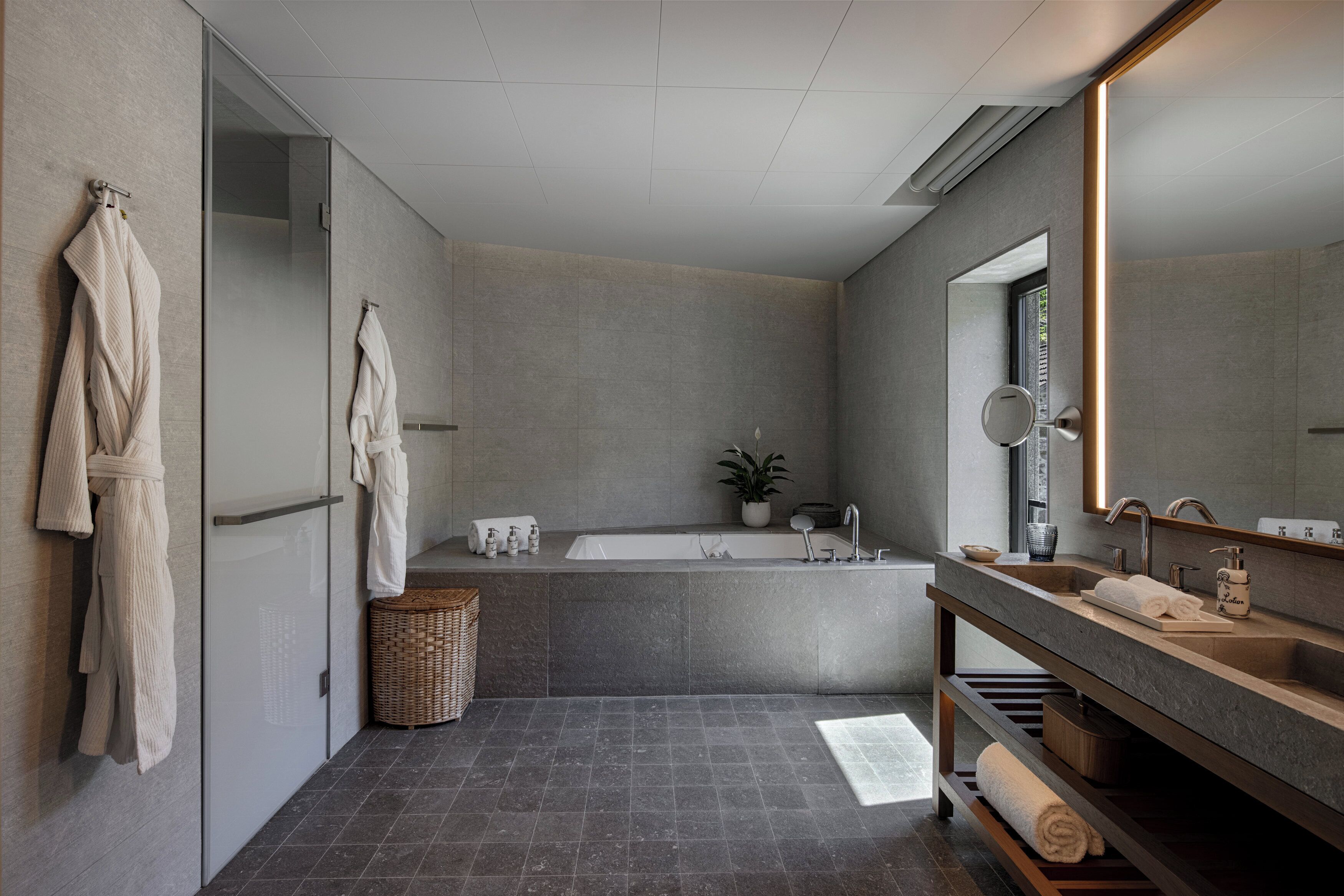 Une salle de bain moderne avec une grande baignoire, un meuble-lavabo avec un miroir et un porte-serviettes fixé au mur.