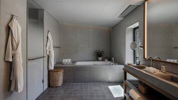Une salle de bain moderne avec une grande baignoire, un meuble-lavabo avec un miroir et un porte-serviettes fixé au mur.