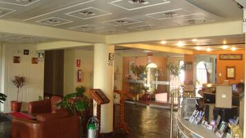Un hall de hotel con mostrador de recepción, zona de estar y una escalera.