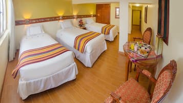 A hotel room with three beds, a dining table with breakfast, and a chair.