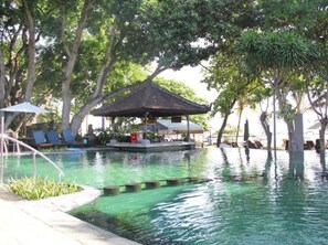 A pool area with lounge chairs and a shaded seating area. - Besakih Beach Hotel (Denpasar)
