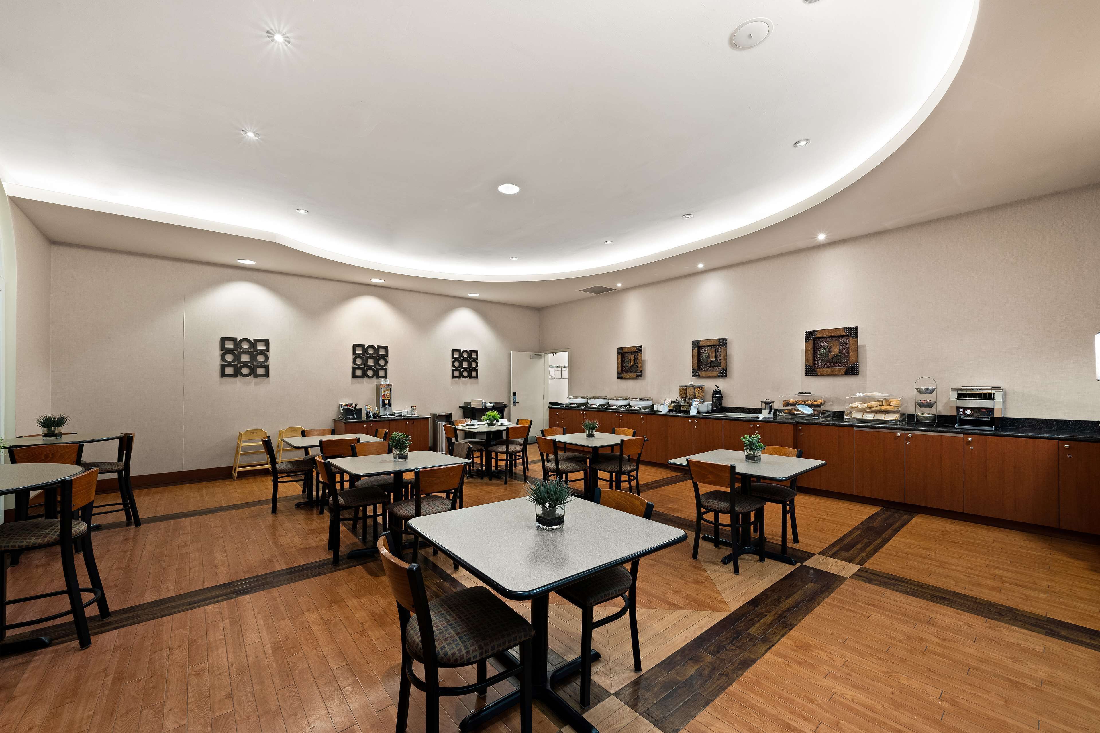 A spacious dining area with multiple tables and chairs, a kitchen counter with appliances, and a clean, modern interior design.