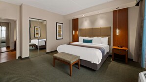Una habitación de hotel con una cama grande, una mesita de noche, un espejo y un taburete pequeño.
