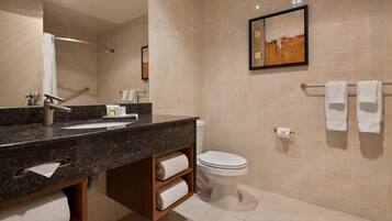 A modern bathroom with a granite countertop, a toilet, and a towel rack.