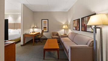 Quarto de hotel com cama, escrivaninha, cadeira, sofá e mesa de centro.