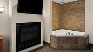 Un baño moderno con un televisor de pantalla plana sobre una chimenea, una bañera independiente y un panel de pared de madera.