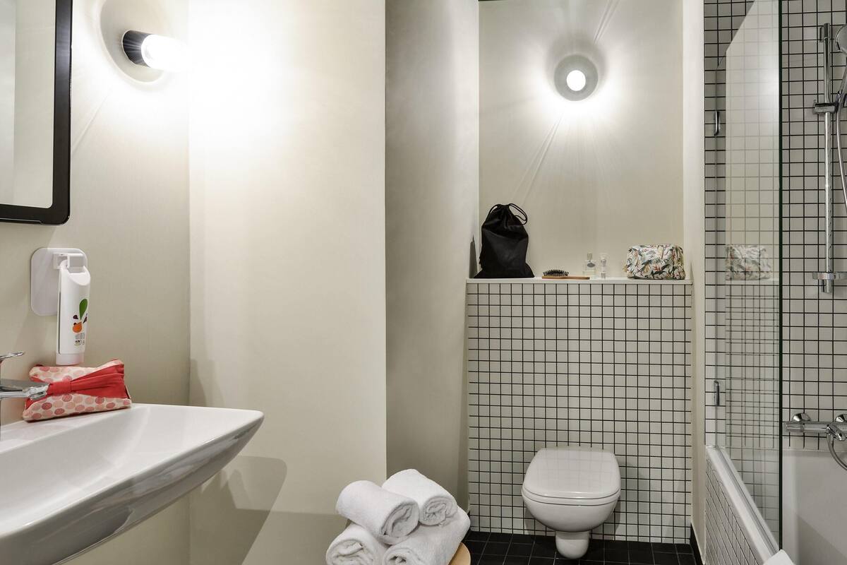 Un baño con lavamanos, inodoro y zona de ducha.