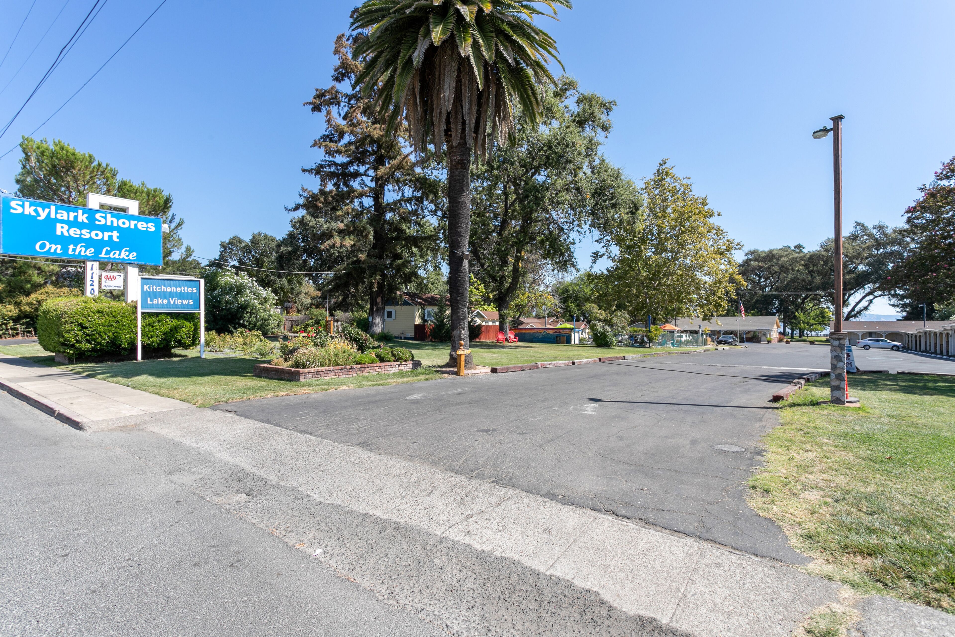 A road leading to a hotel named Skylark Shores Resort, with a sign indicating 'On the Lake' and 'Kitchenettes Lake Views'.
