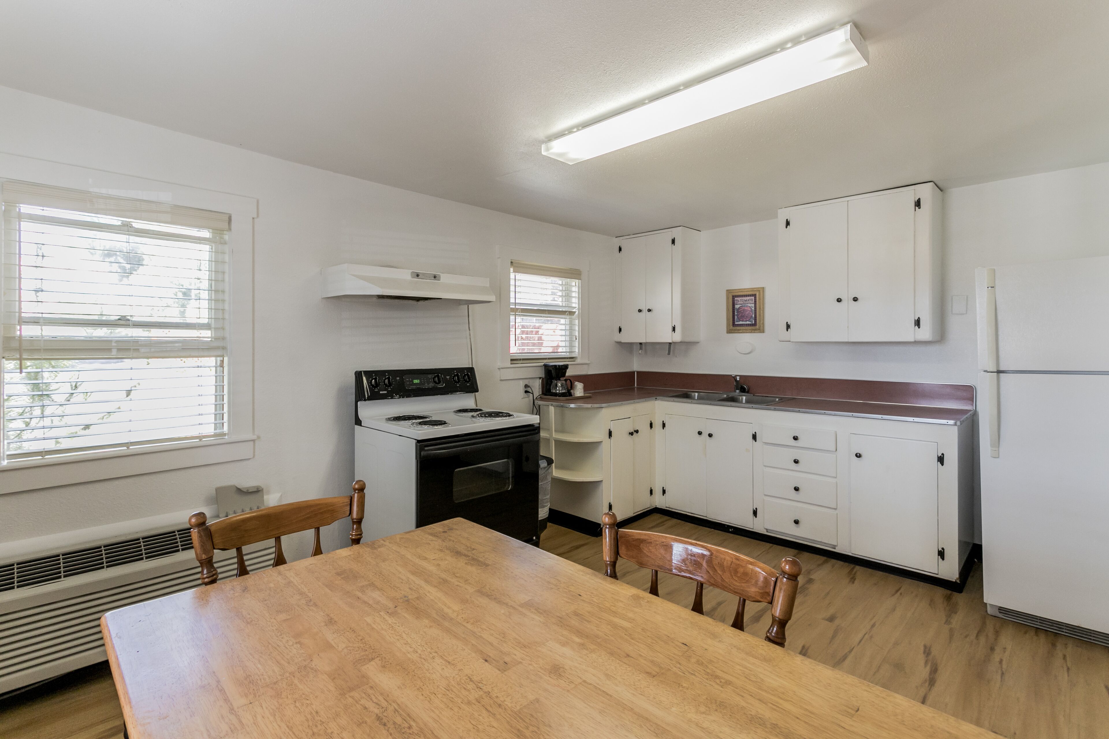 A kitchen with white cabinets, a stove, and a dining table with chairs.