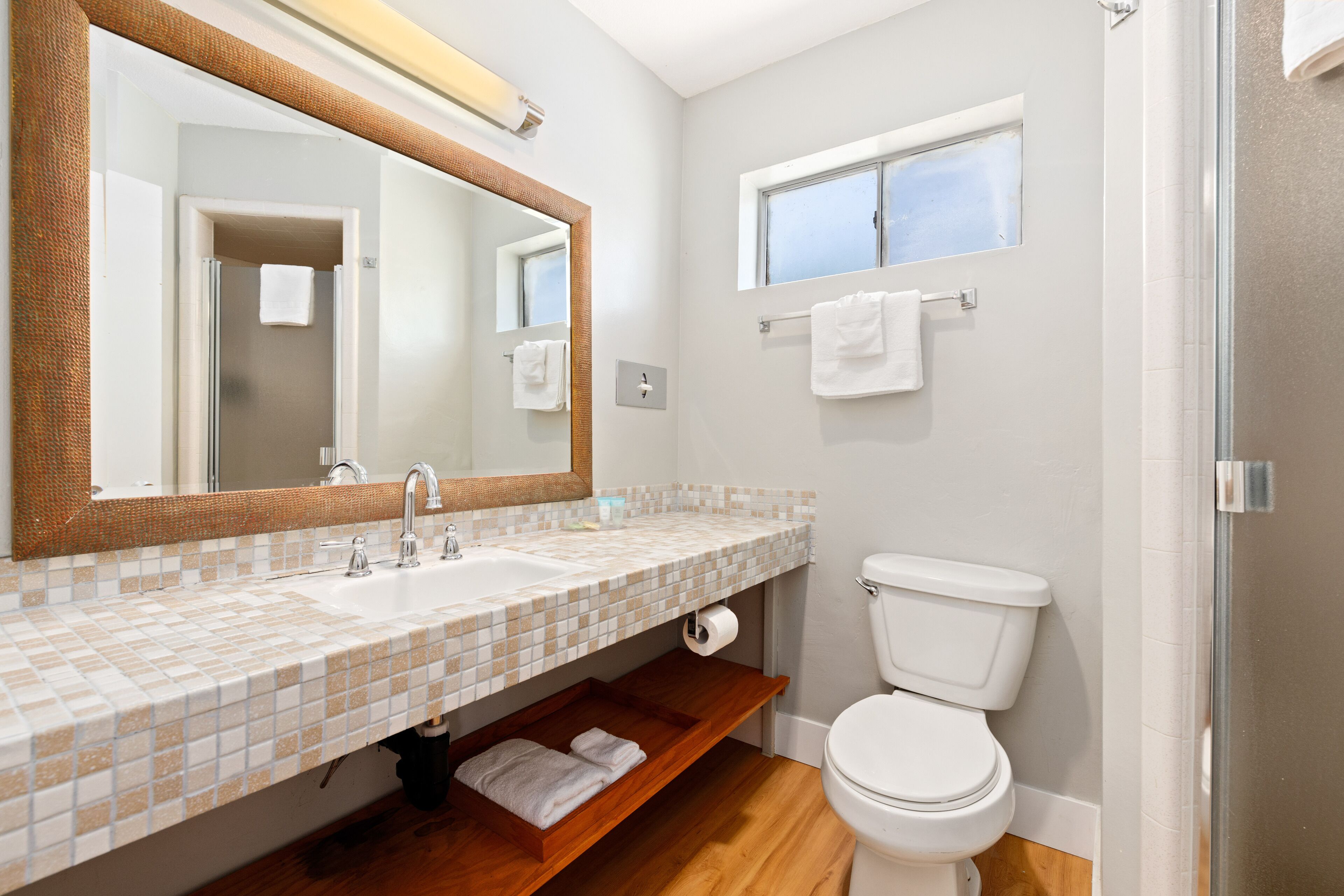 Ein Badezimmer mit Waschbecken, Spiegel, Toilette und Fenster.