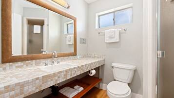 Ein Badezimmer mit Waschbecken, Spiegel, Toilette und Fenster.
