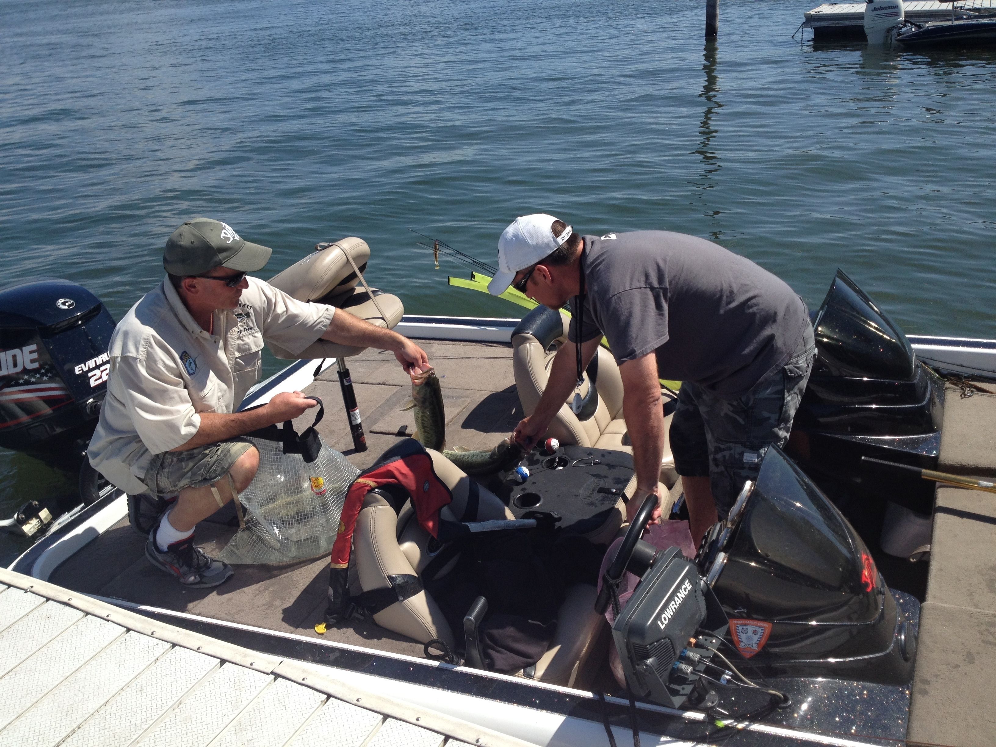 Two men on a boat preparing fishing equipment.