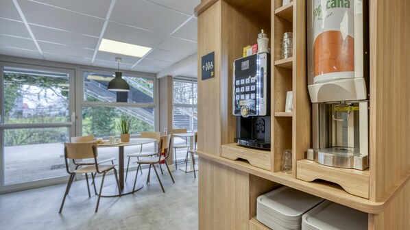 A coffee station with a coffee machine, a refrigerator, and a sign indicating a disabled parking space. - PREMIERE CLASSE VILLEPINTE CENTRE - Parc des Expositions (Villepinte)