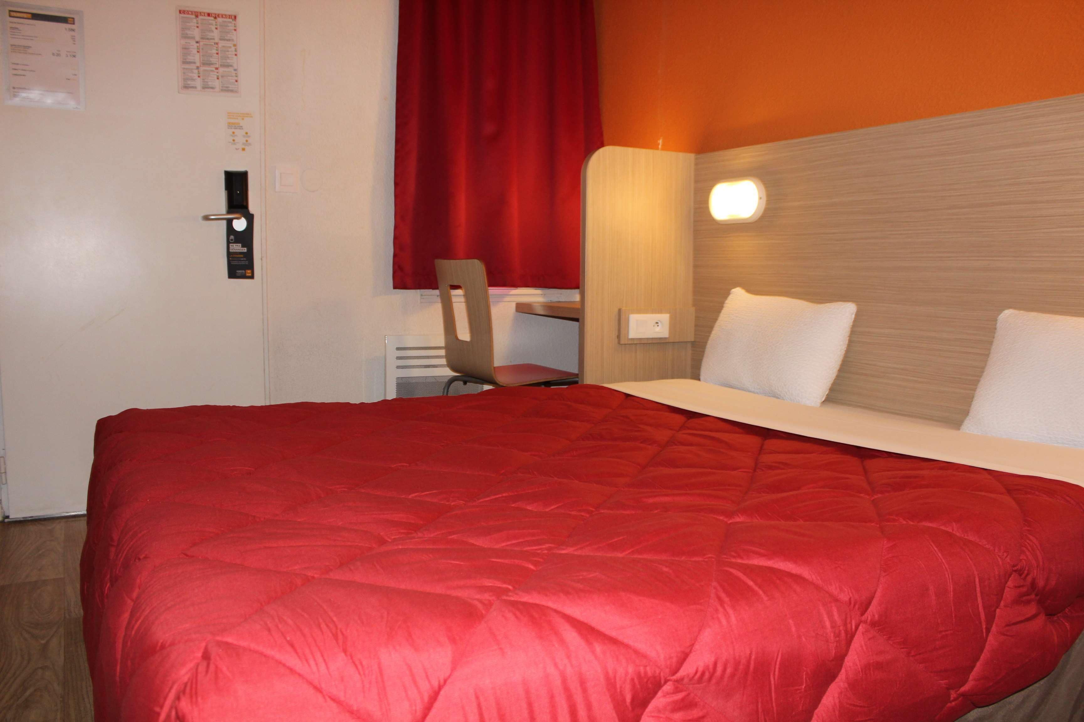 Une chambre d’hôtel avec un grand lit, un bureau et une chaise.