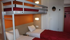 Habitación con literas, una puerta y una lámpara fijada a la pared.