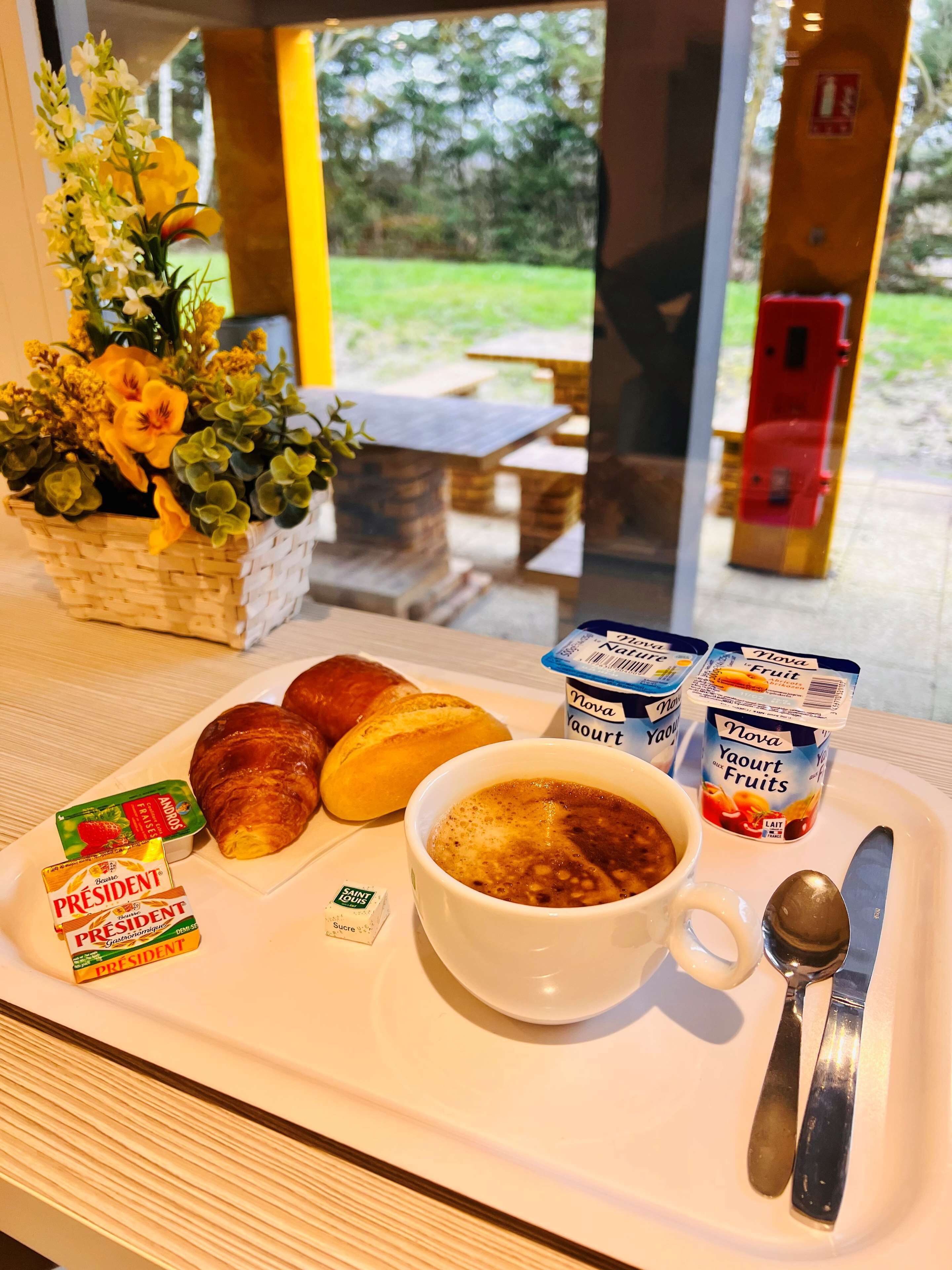 Een ontbijttafel met croissants, een kom soep, yoghurt en een zakje suiker.