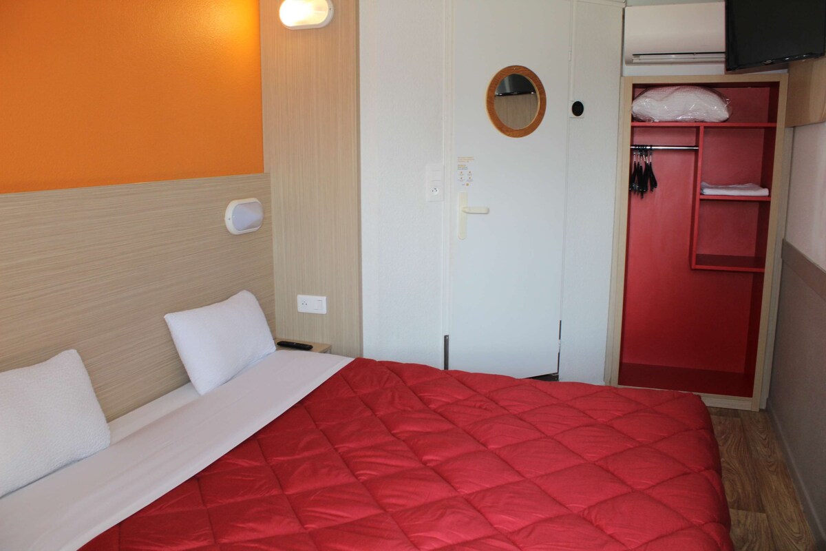 Una habitación de hotel con cama, armario, espejo y televisor.