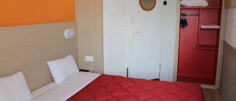 Una habitación de hotel con cama, armario, espejo y televisor.