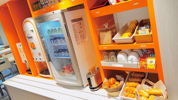 Una barra de desayuno equipada con refrigerador, tostadora y cestas de pan y pasteles.
