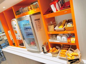 Una barra de desayuno equipada con refrigerador, tostadora y cestas de pan y pasteles.