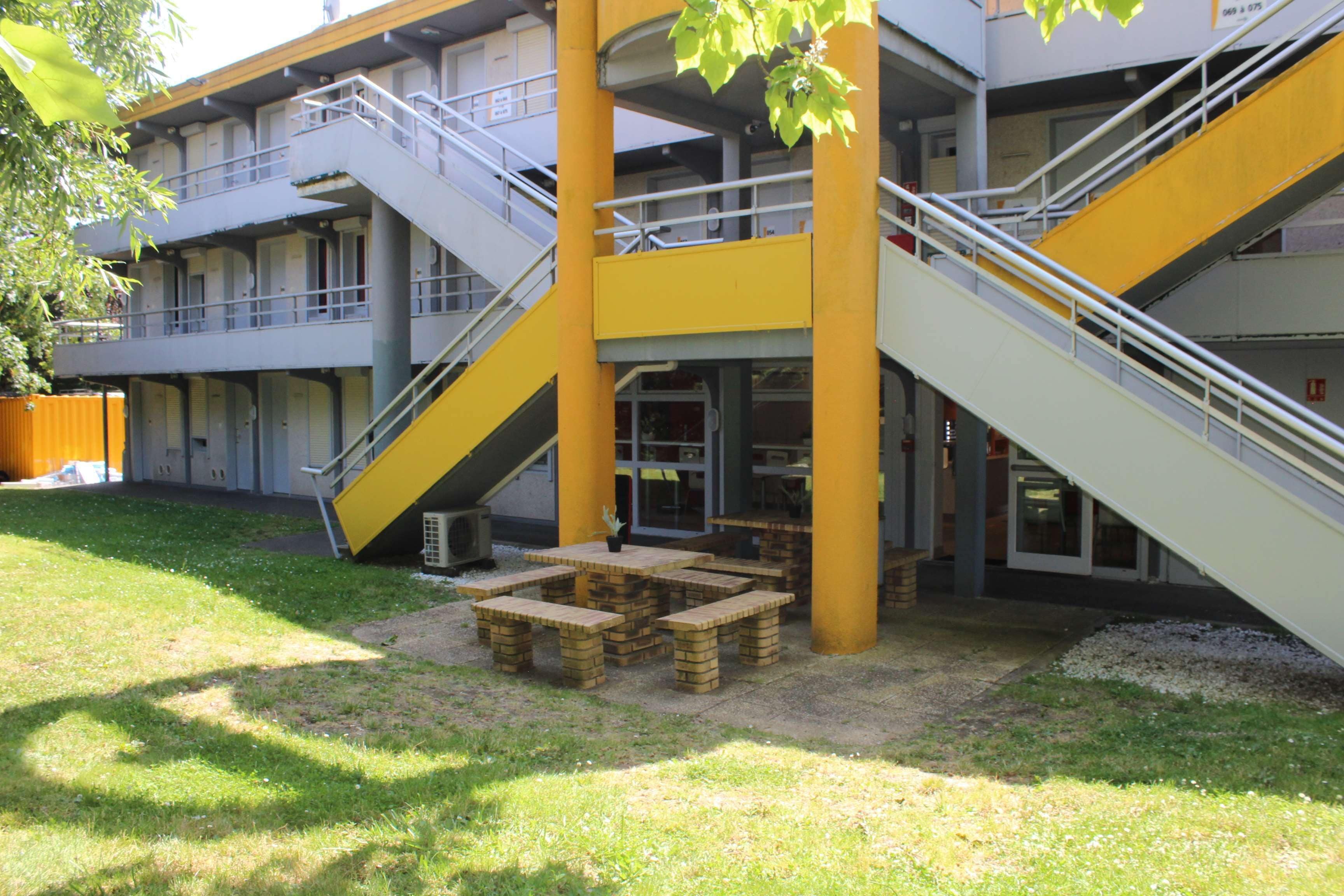 A building with multiple floors, outdoor seating area, and a staircase.