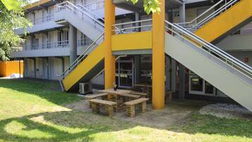 A building with multiple floors, outdoor seating area, and a staircase.