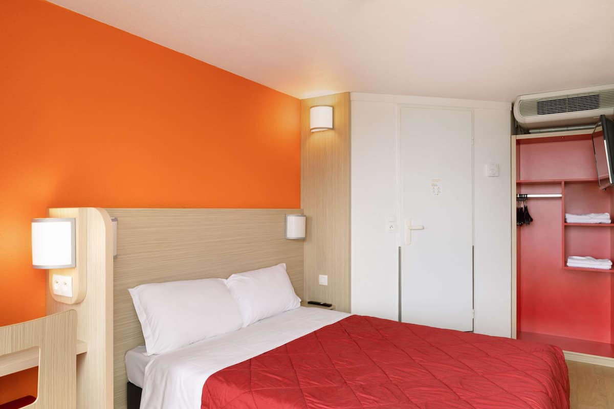A hotel room with a bed, a wardrobe, and a seating area.