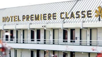 Een hotel genaamd "HOTEL PREMIERE CLASSE" met een rij kamers en een balkon.