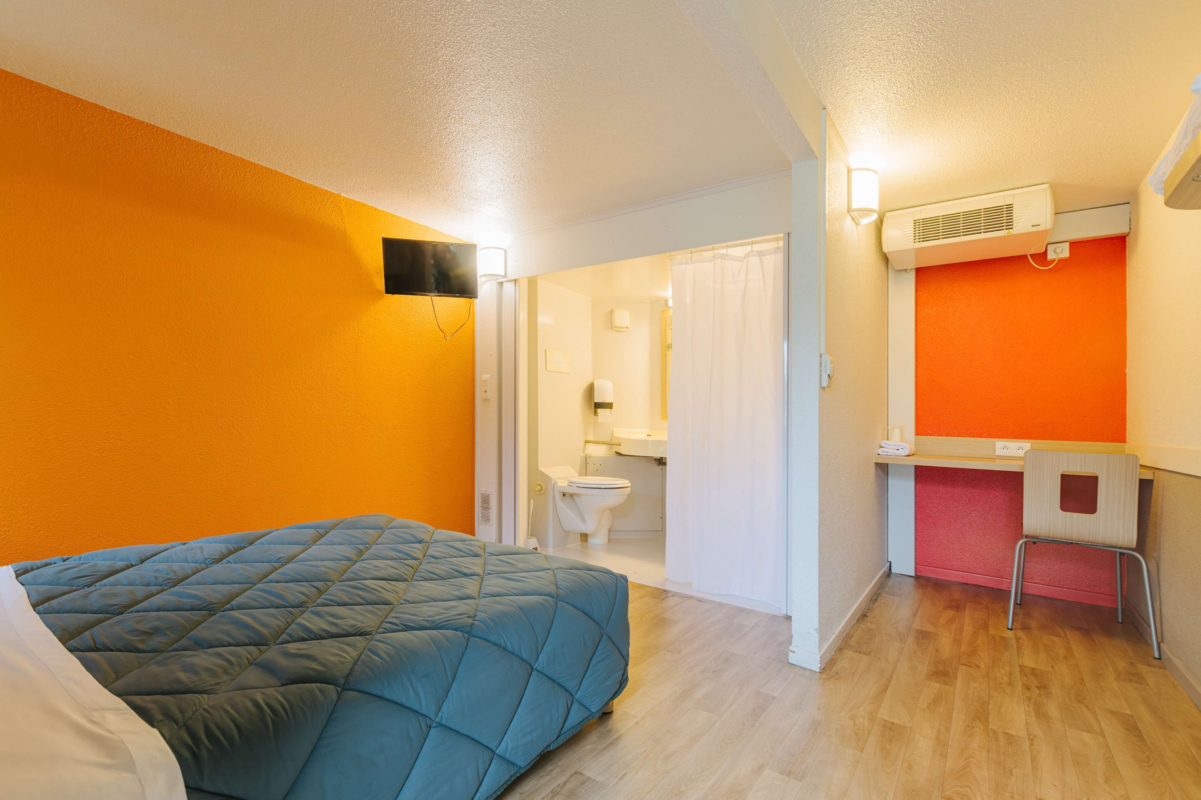 A room with a bed, a desk, and a bathroom.