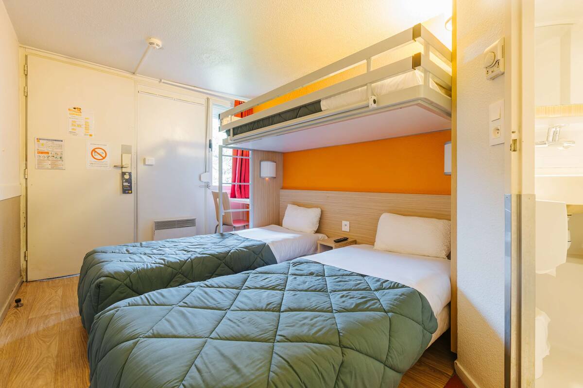 A hotel room with bunk beds, a desk, and a chair.