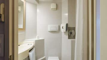 A bathroom with a toilet, sink, and mirror. There is a towel hanging on the wall and a soap dispenser.