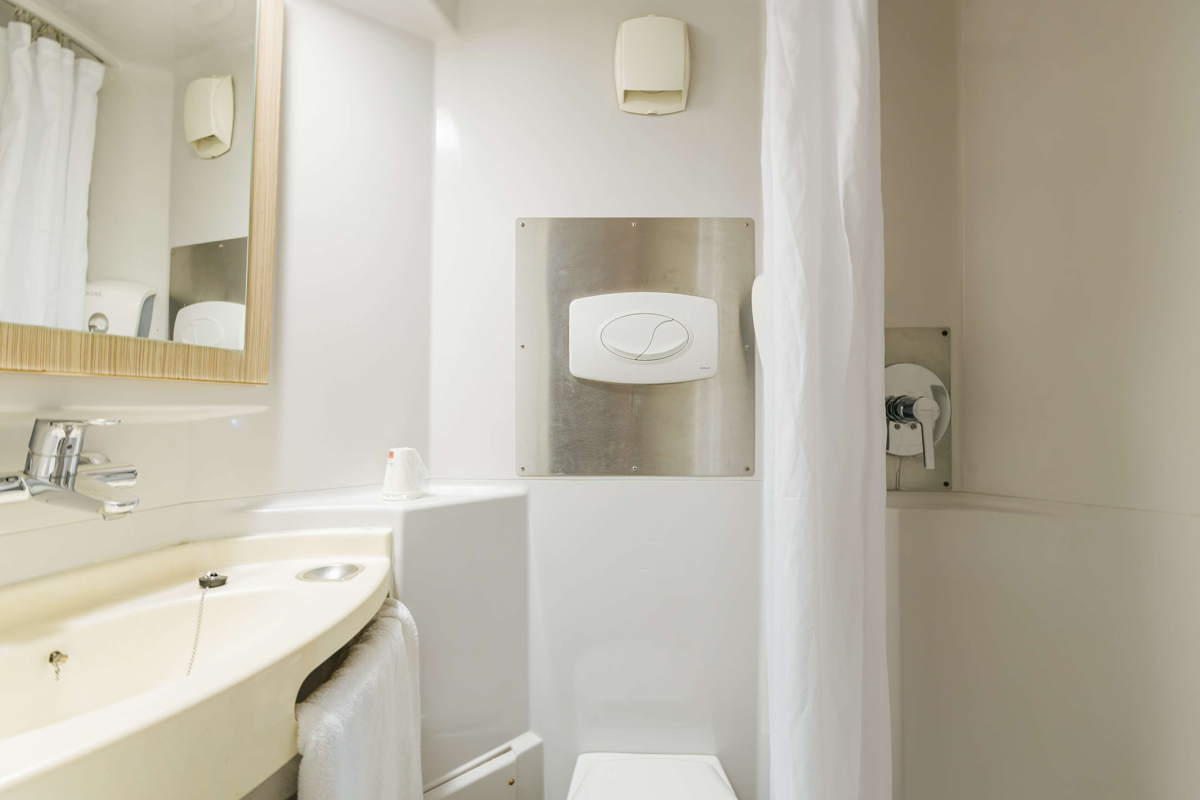 A modern bathroom with a sink, mirror, towel rack, and a shower area.