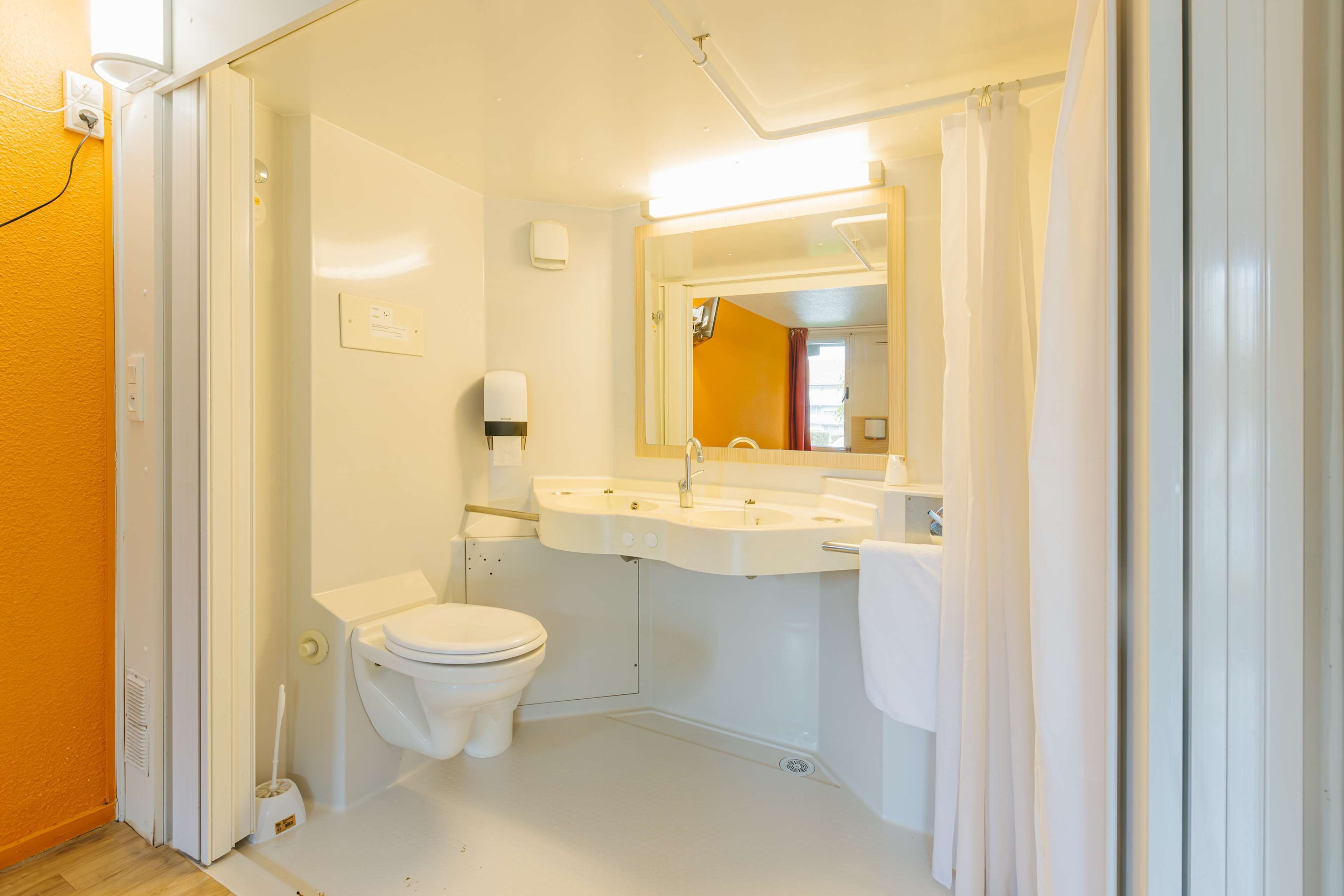 A small, clean bathroom with a toilet, sink, and mirror.