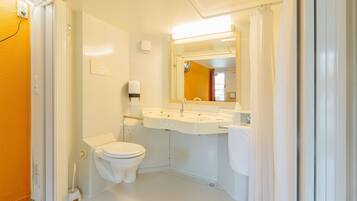 A small, clean bathroom with a toilet, sink, and mirror.