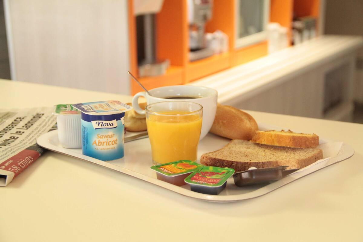 A breakfast tray with Nova yogurt, orange juice, and toast on a table.