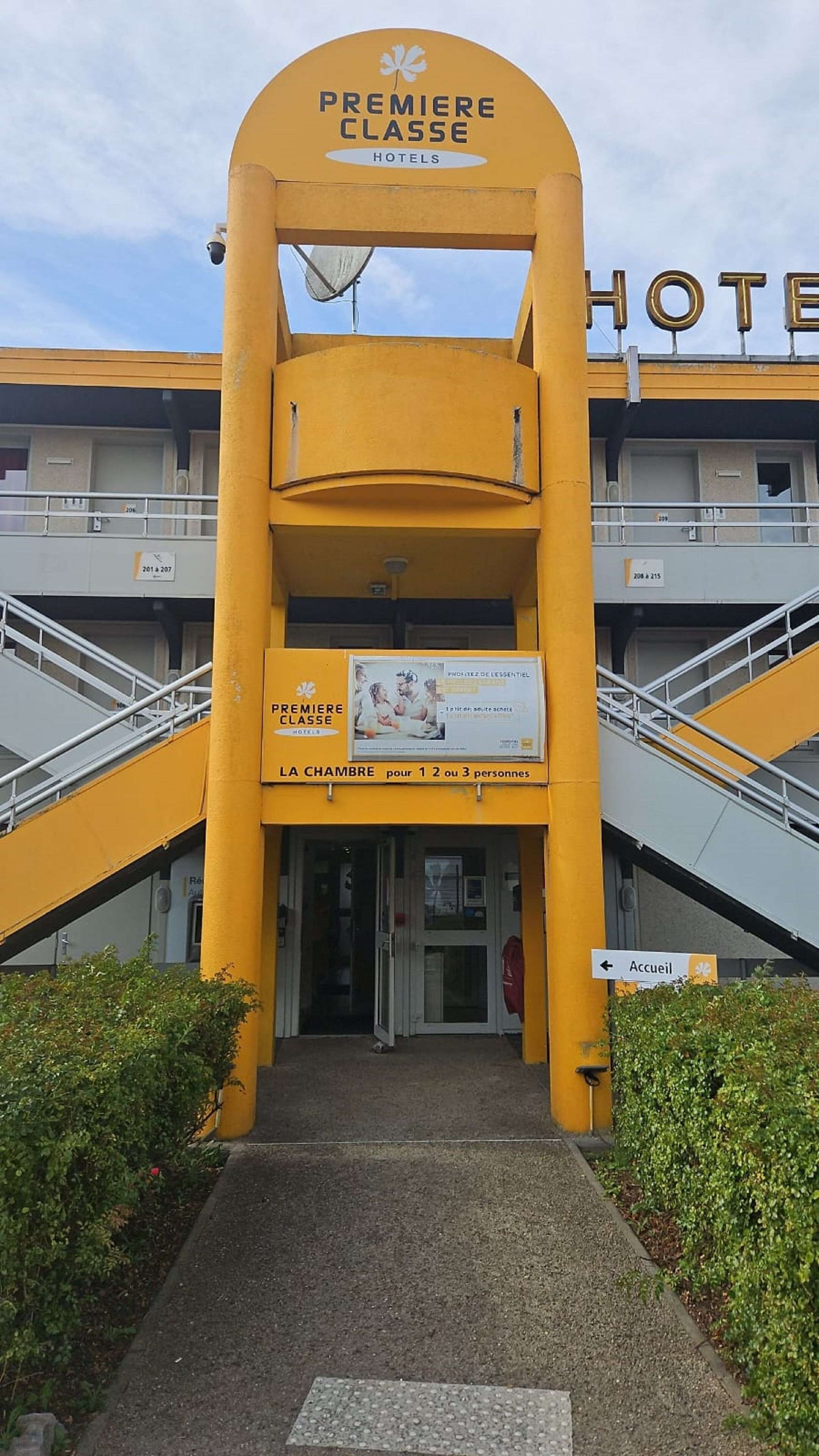 Entrada de un hotel con un llamativo arco amarillo y señalización que indica que es un hotel Premiere Classe.