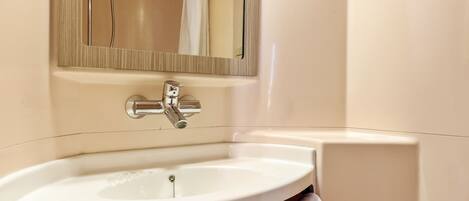 Un baño con un lavamanos blanco, un espejo y una ducha.