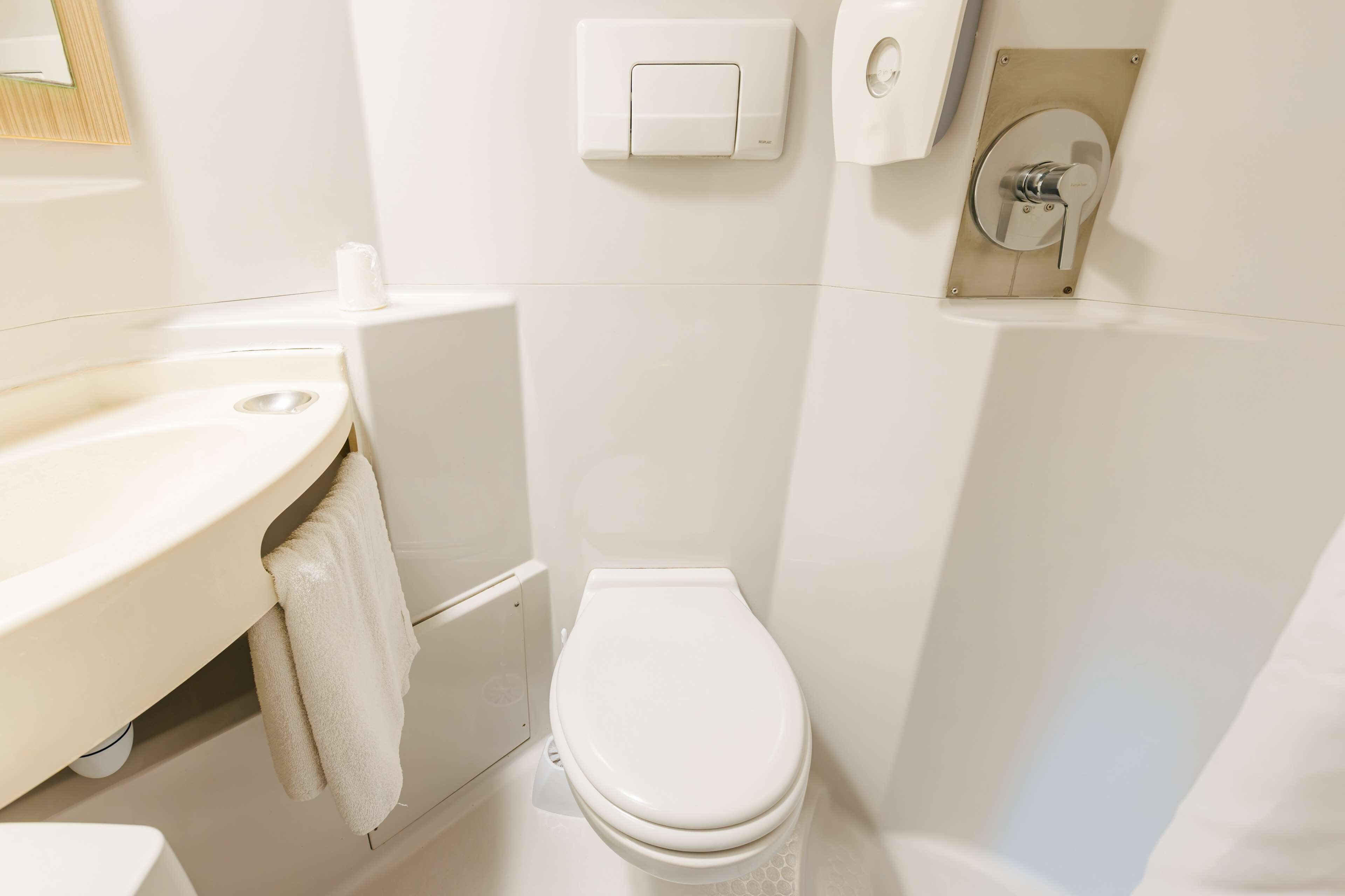 Un baño pequeño y limpio con inodoro, lavabo y toallero.