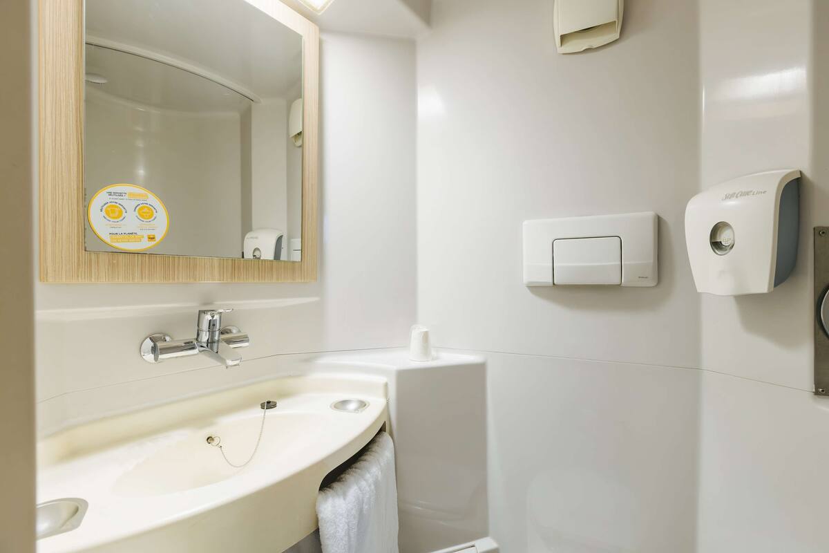 A modern bathroom with a sink, mirror, and hand dryer.