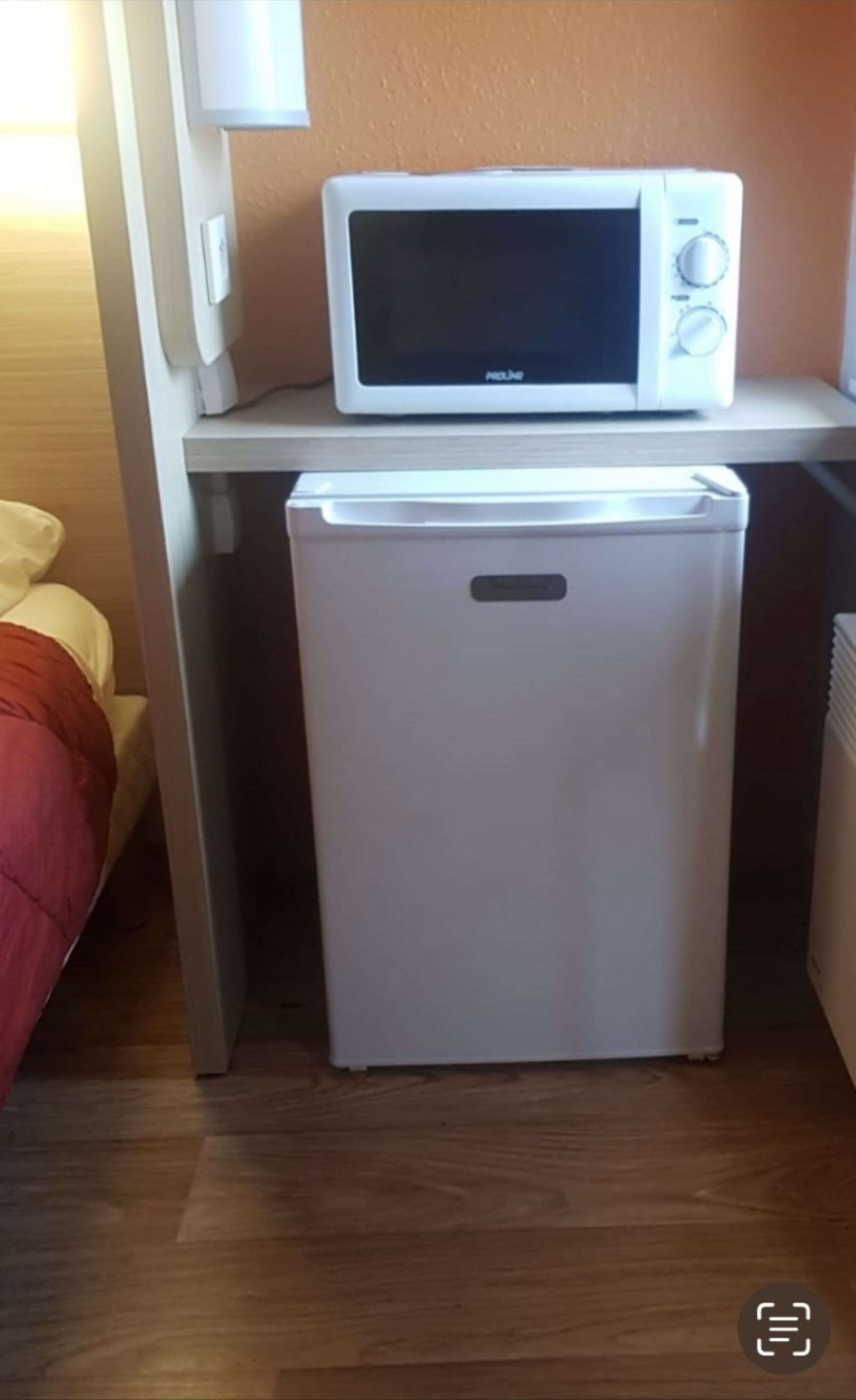 Een kleine keuken met een magnetron en een minibar.