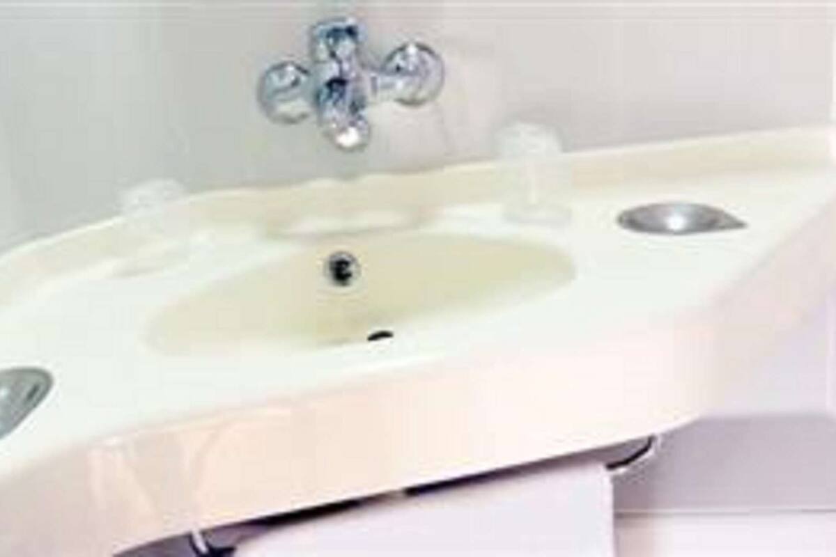 Une salle de bain avec un lavabo blanc, un robinet et un miroir.