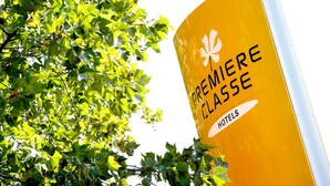 Ein gelbes Schild mit der Aufschrift 'PREMIERE CLASSE HOTELS' und einem weißen Ahornblatt-Symbol.