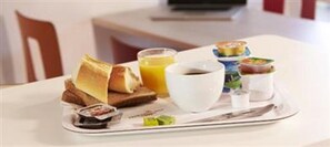 A breakfast tray with toast, orange juice, coffee, and small dishes of food on a hotel table. - Premiere Classe Evreux (Evreux)